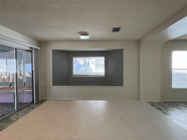 unfurnished room with a textured ceiling and plenty of natural light