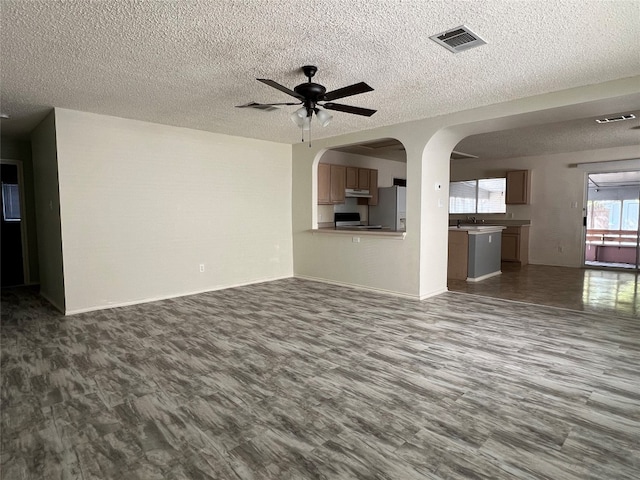 unfurnished living room with ceiling fan, a textured ceiling, and hardwood / wood-style flooring