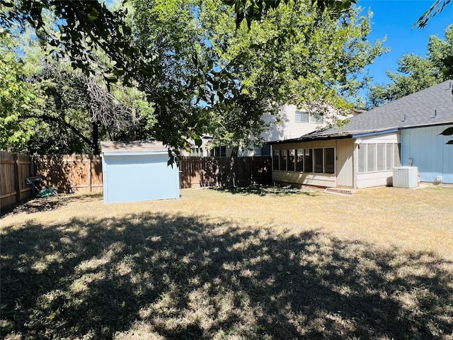 view of yard featuring central air condition unit, a sunroom, and a storage shed