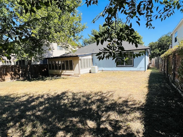 back of property with a lawn and a sunroom