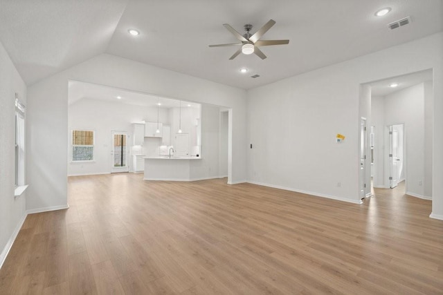 unfurnished living room featuring ceiling fan, lofted ceiling, sink, and light wood-type flooring