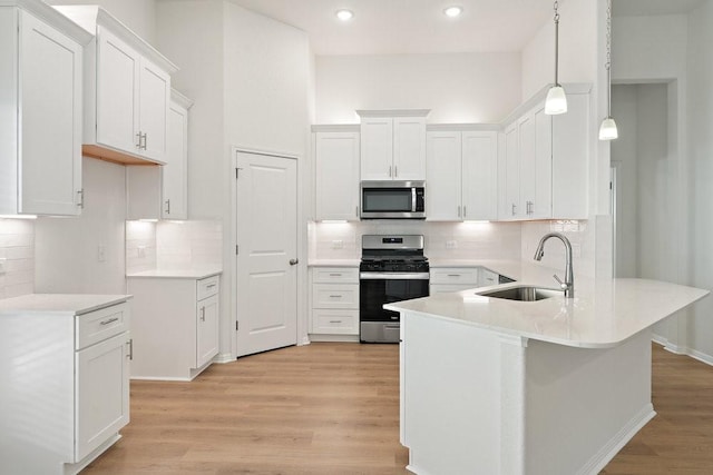 kitchen featuring sink, decorative light fixtures, light wood-type flooring, stainless steel appliances, and white cabinets