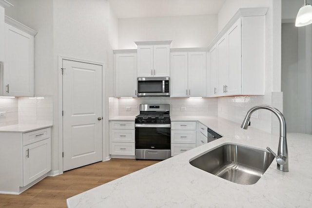 kitchen with appliances with stainless steel finishes, sink, and white cabinets