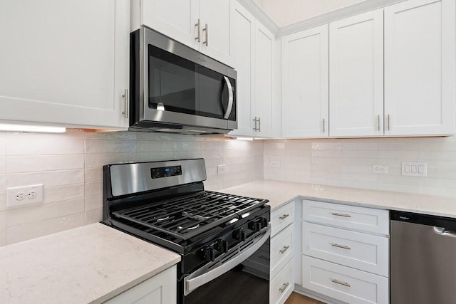 kitchen featuring light stone countertops, white cabinetry, appliances with stainless steel finishes, and backsplash