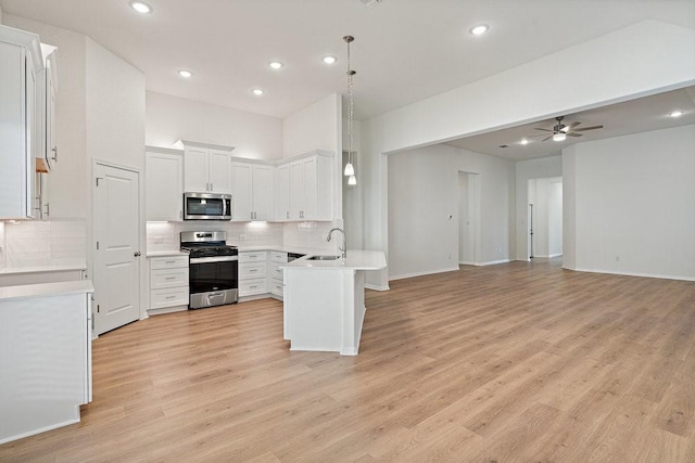 kitchen featuring white cabinetry, tasteful backsplash, kitchen peninsula, pendant lighting, and stainless steel appliances