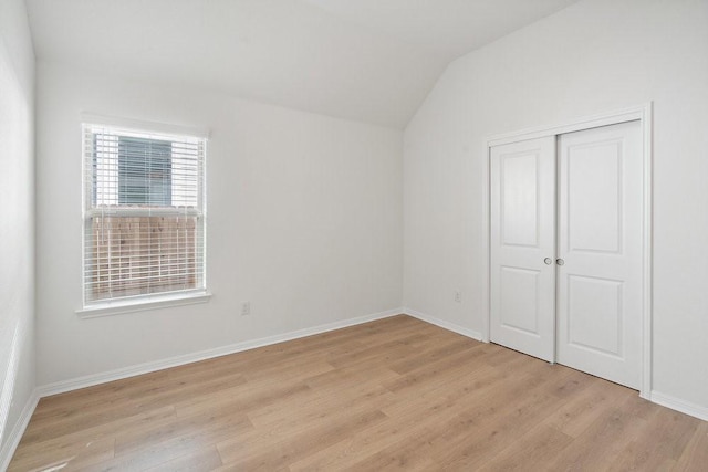 unfurnished bedroom with vaulted ceiling, light hardwood / wood-style flooring, and a closet