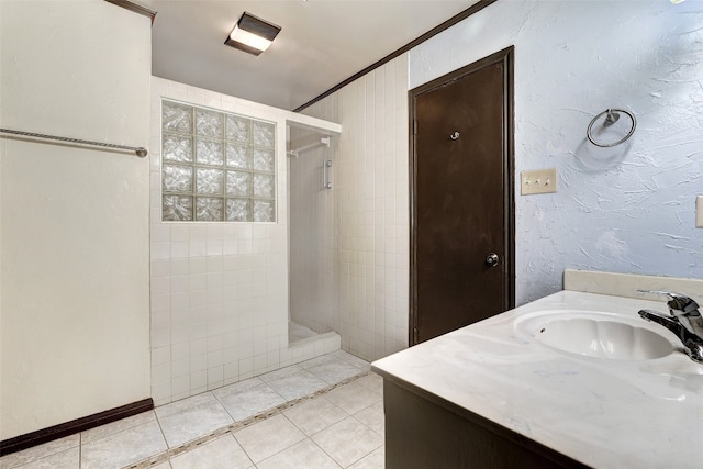 bathroom featuring vanity, ornamental molding, tile patterned floors, and tiled shower