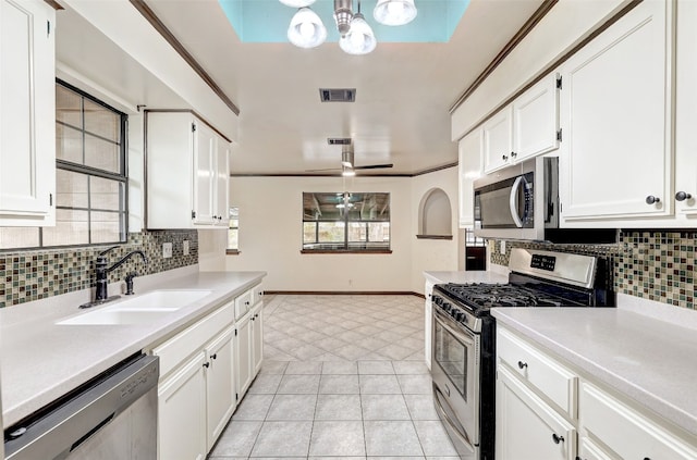 kitchen featuring white cabinets, backsplash, ornamental molding, sink, and stainless steel appliances