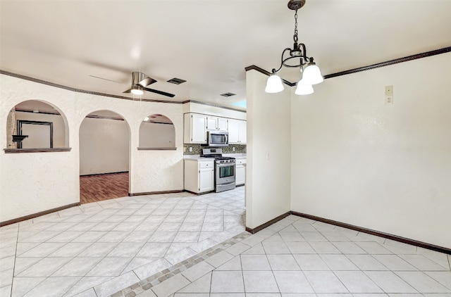 kitchen featuring appliances with stainless steel finishes, ceiling fan with notable chandelier, white cabinetry, pendant lighting, and ornamental molding