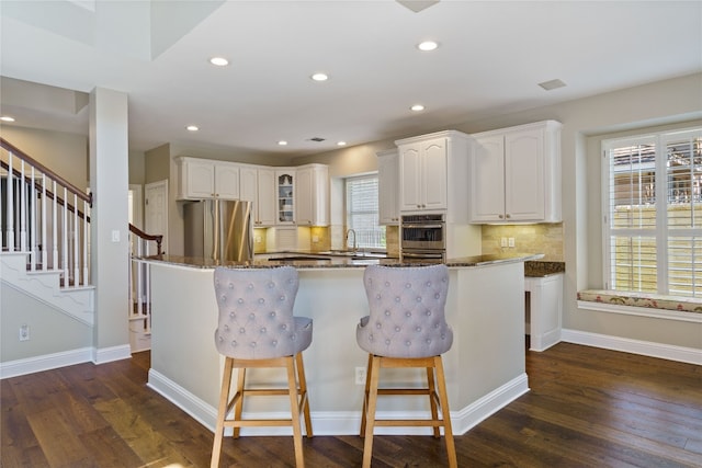 kitchen featuring stainless steel refrigerator, dark stone counters, dark wood-type flooring, and white cabinets