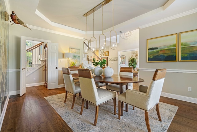 dining area with dark hardwood / wood-style flooring, a tray ceiling, ornamental molding, and an inviting chandelier