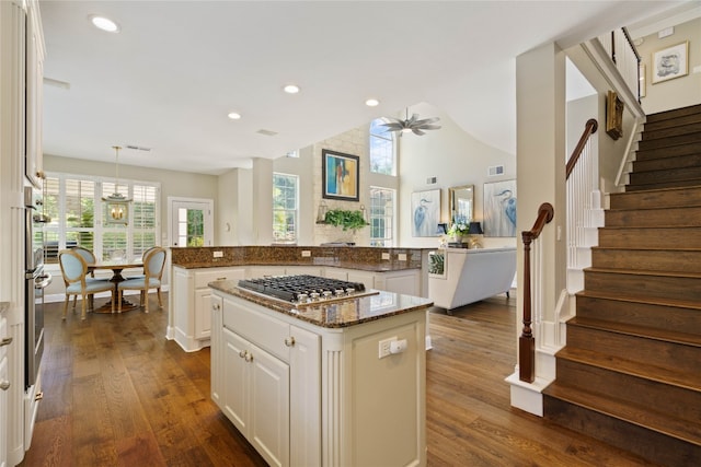 kitchen with white cabinetry, stainless steel appliances, a center island, and dark stone counters