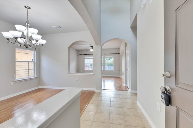 foyer entrance featuring light hardwood / wood-style floors, ceiling fan with notable chandelier, and a wealth of natural light