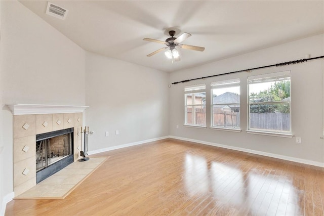 7537 S Glenn St, Austin, TX 78744 - unfurnished living room with a tiled fireplace, ceiling fan, wood finished floors, and baseboards