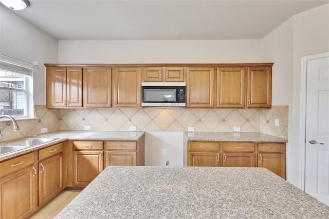 7537 S Glenn St, Austin, TX 78744 - kitchen with stainless steel microwave, a sink, backsplash, and light stone counters