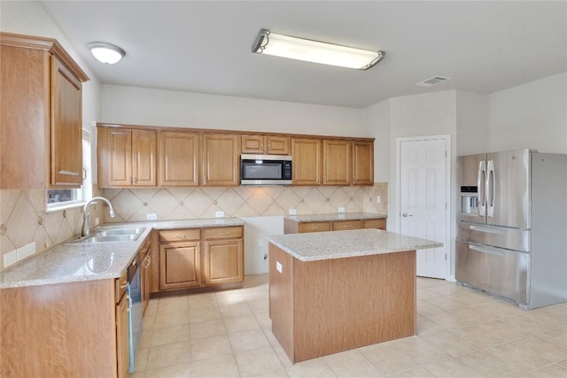 7537 S Glenn St, Austin, TX 78744 - kitchen featuring appliances with stainless steel finishes, a sink, brown cabinets, light stone countertops, and decorative backsplash