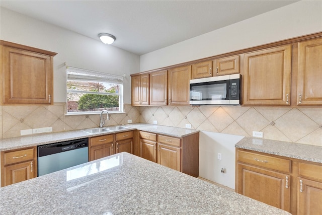 kitchen with sink, light stone counters, stainless steel appliances, and backsplash