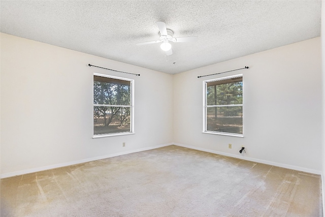 empty room with ceiling fan, a textured ceiling, and light colored carpet