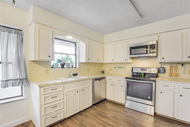 kitchen featuring dark wood-type flooring, appliances with stainless steel finishes, sink, and white cabinets