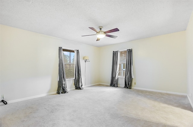 empty room with a textured ceiling, light colored carpet, and ceiling fan