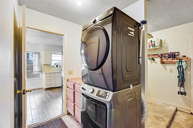 washroom featuring stacked washer / dryer, a textured ceiling, and light hardwood / wood-style flooring