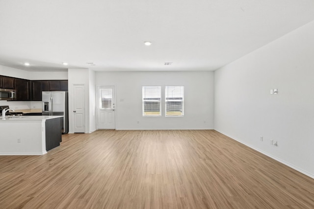 unfurnished living room featuring sink and light hardwood / wood-style floors