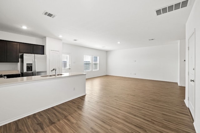 kitchen with stainless steel fridge, dark brown cabinetry, sink, and dark hardwood / wood-style floors