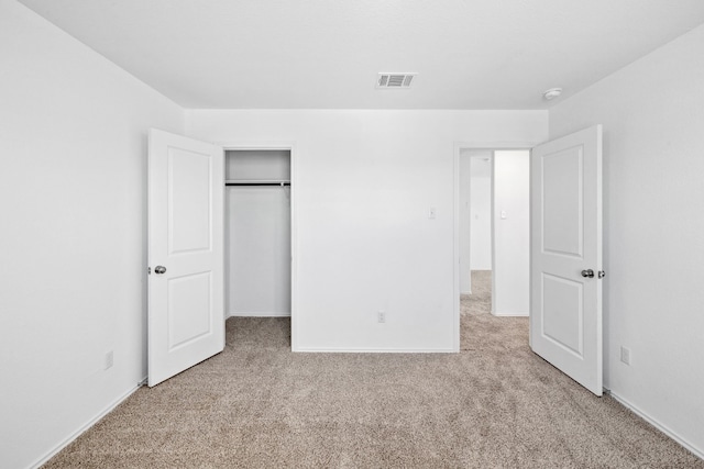 unfurnished bedroom with a closet and light colored carpet