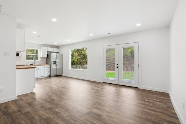 unfurnished living room with sink, french doors, dark hardwood / wood-style floors, and plenty of natural light