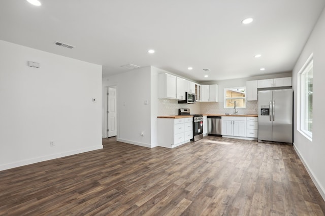 kitchen with white cabinets, tasteful backsplash, wood-type flooring, butcher block counters, and stainless steel appliances