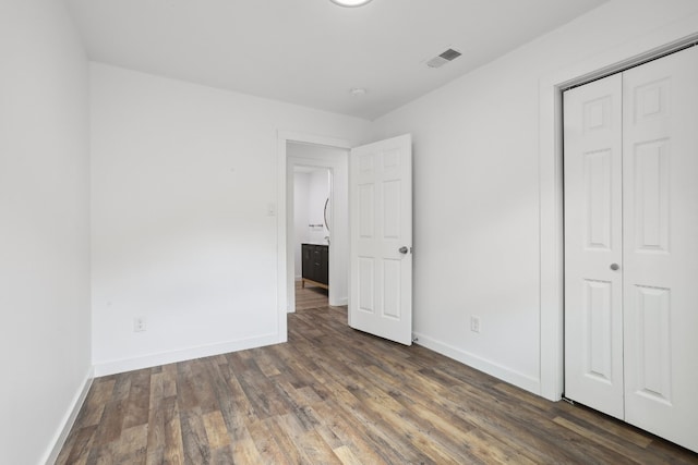 unfurnished bedroom featuring a closet and dark hardwood / wood-style floors