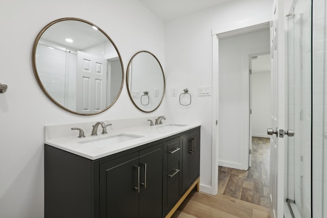 bathroom with vanity, a shower with shower door, and wood-type flooring