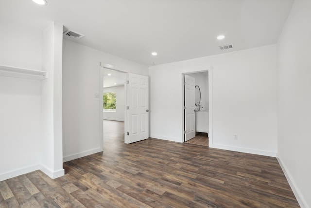 unfurnished bedroom with a closet, ensuite bathroom, and dark hardwood / wood-style floors