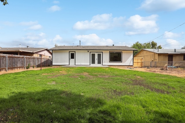 back of house with french doors and a lawn