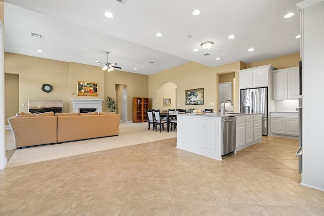 kitchen featuring ceiling fan, appliances with stainless steel finishes, an island with sink, and white cabinets