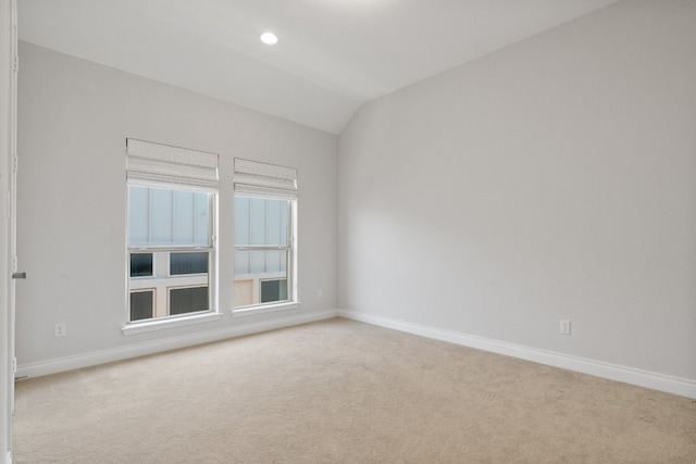 carpeted empty room featuring vaulted ceiling