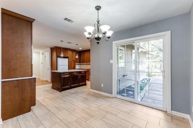 kitchen with pendant lighting, a chandelier, white fridge, and a center island