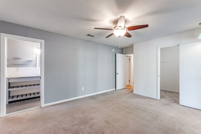 unfurnished bedroom with light colored carpet, ceiling fan, and a spacious closet