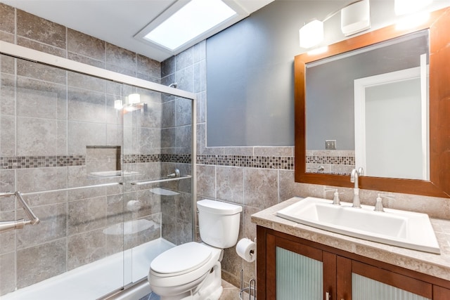 bathroom with a shower with door, vanity, toilet, and tile walls