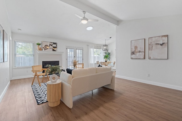 living room featuring ceiling fan, beam ceiling, and wood-type flooring