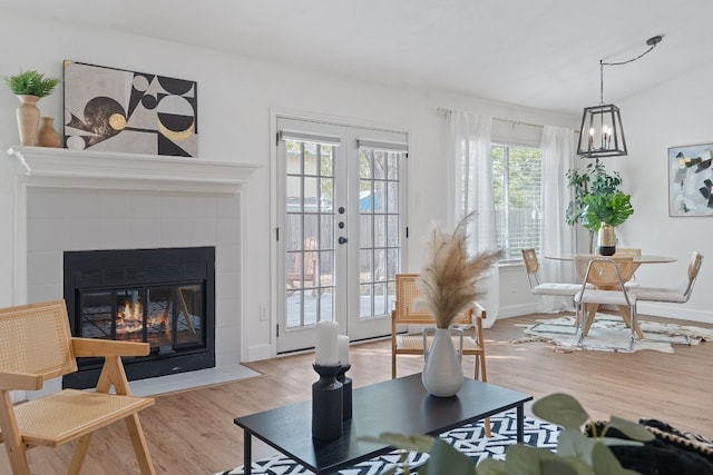 sitting room with french doors, a tile fireplace, and light hardwood / wood-style flooring