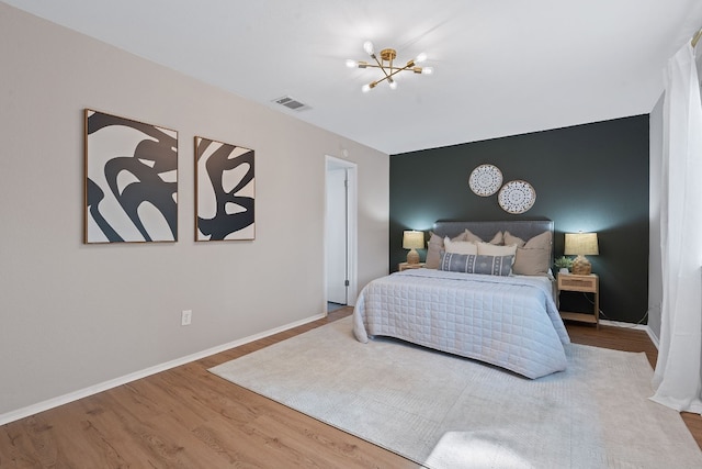 bedroom featuring wood-type flooring and an inviting chandelier