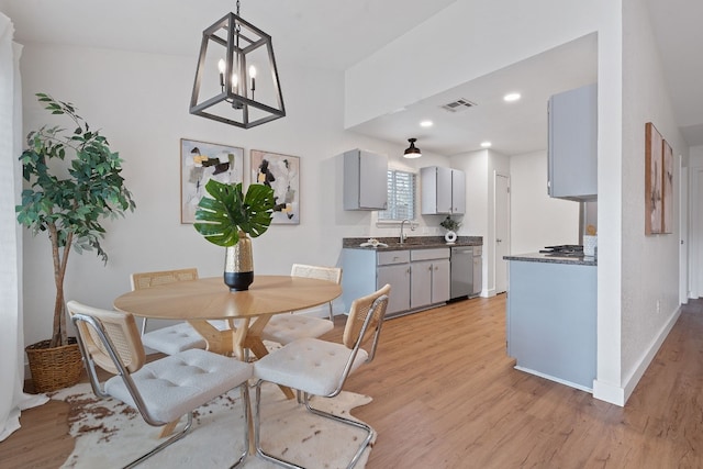 dining area featuring sink, light hardwood / wood-style flooring, and a notable chandelier