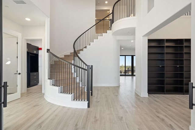 stairs featuring hardwood / wood-style floors and a high ceiling