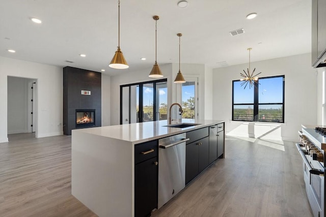 kitchen featuring a center island with sink, decorative light fixtures, sink, and stainless steel appliances