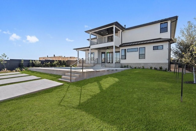 rear view of house with a yard, a balcony, and a patio