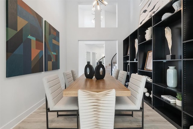 dining space featuring light wood-type flooring, stairway, baseboards, and an inviting chandelier