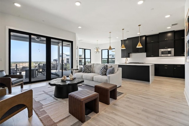 living room with visible vents, light wood finished floors, a wealth of natural light, and recessed lighting