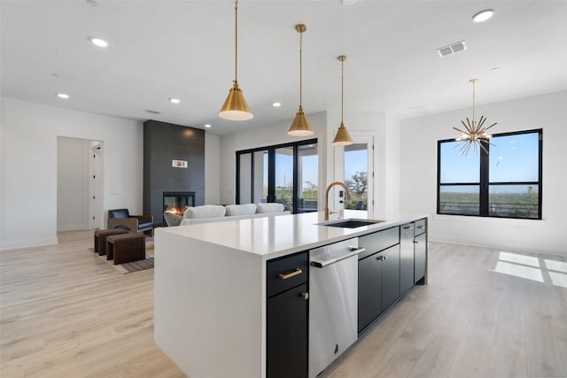 kitchen featuring a large fireplace, light wood finished floors, visible vents, a sink, and stainless steel dishwasher