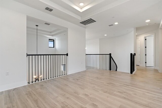 spare room featuring a tray ceiling, visible vents, and wood finished floors